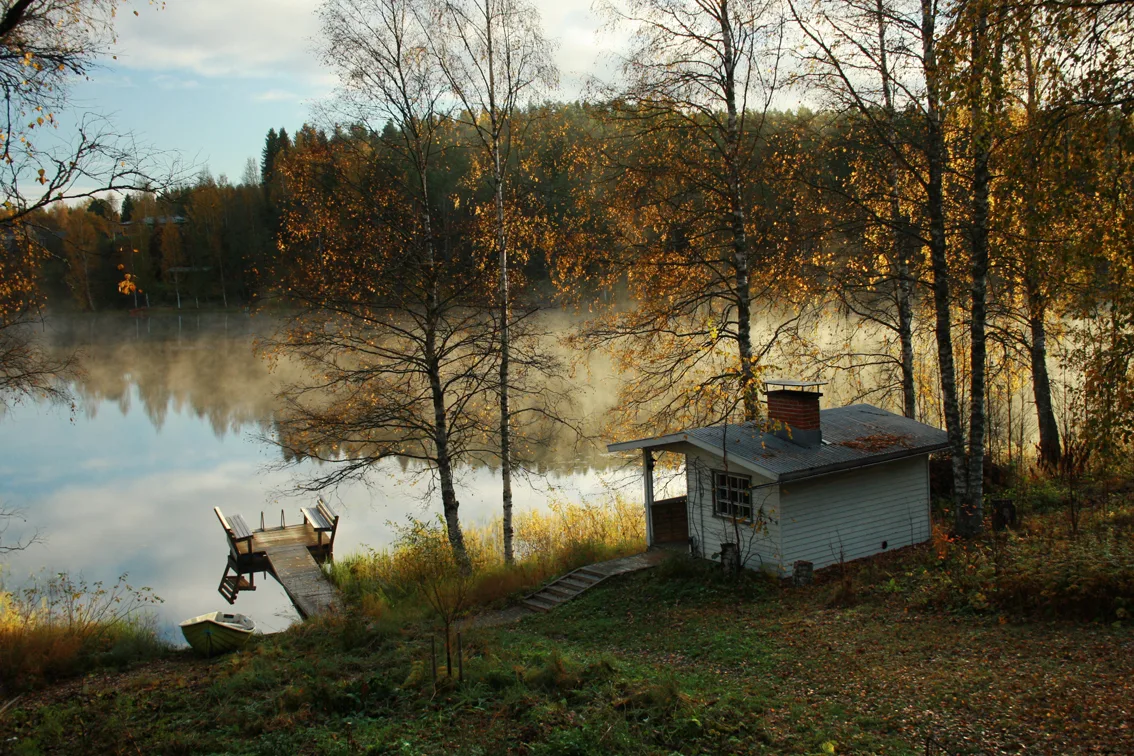 Mökkisauna järven rannalla syysaamun valossa